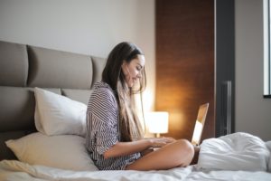 woman sitting in bed doing work