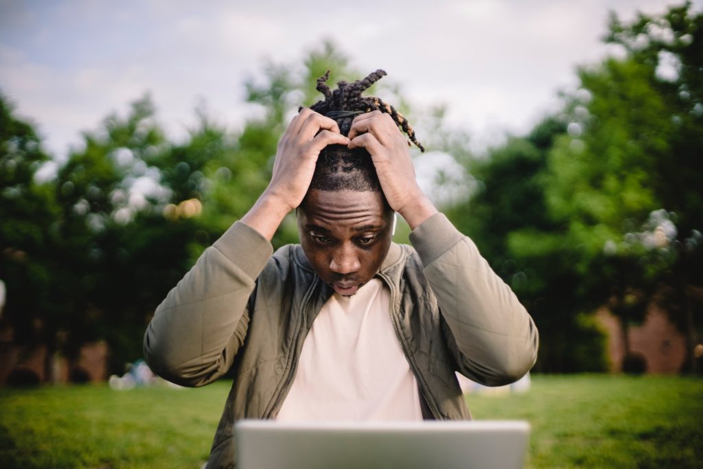 Man in front of a laptop, pulling his hair